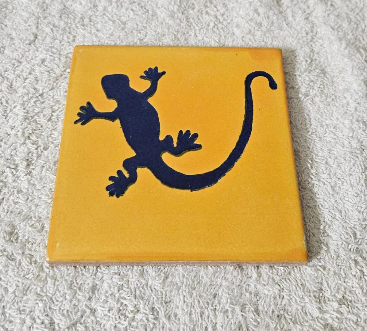 Tile with black lizard silhouette on orange.