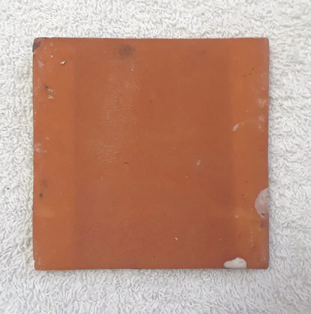 Worn square terracotta tile with chips