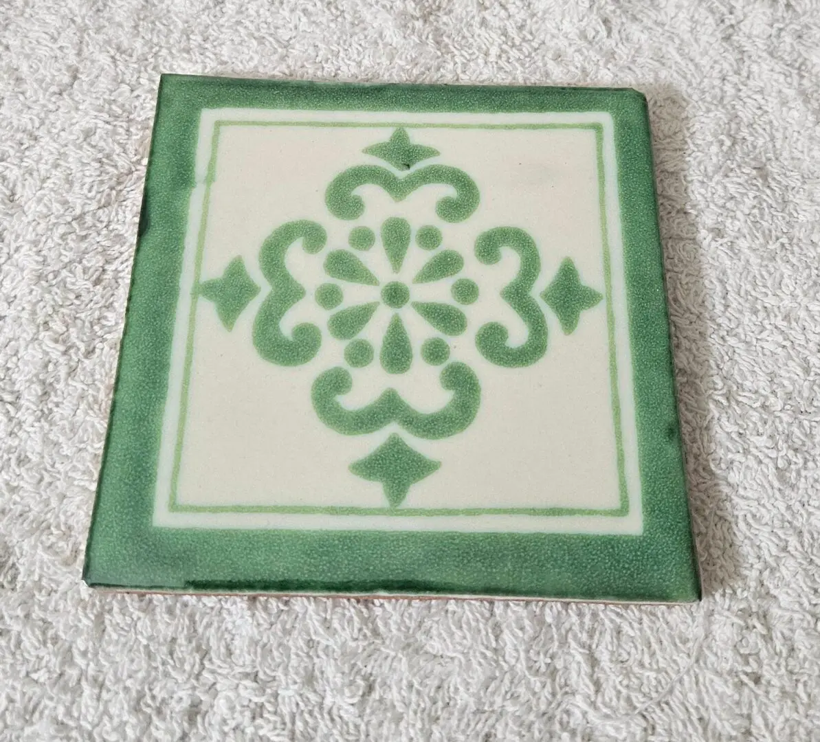 Green ornamental ceramic tile on white towel