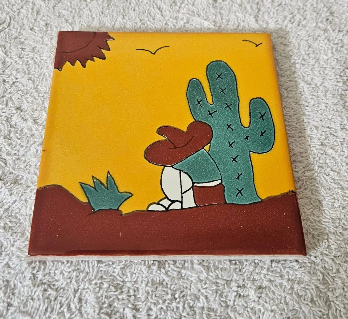 Decorative tile with a southwestern desert scene featuring a cactus and a bird.