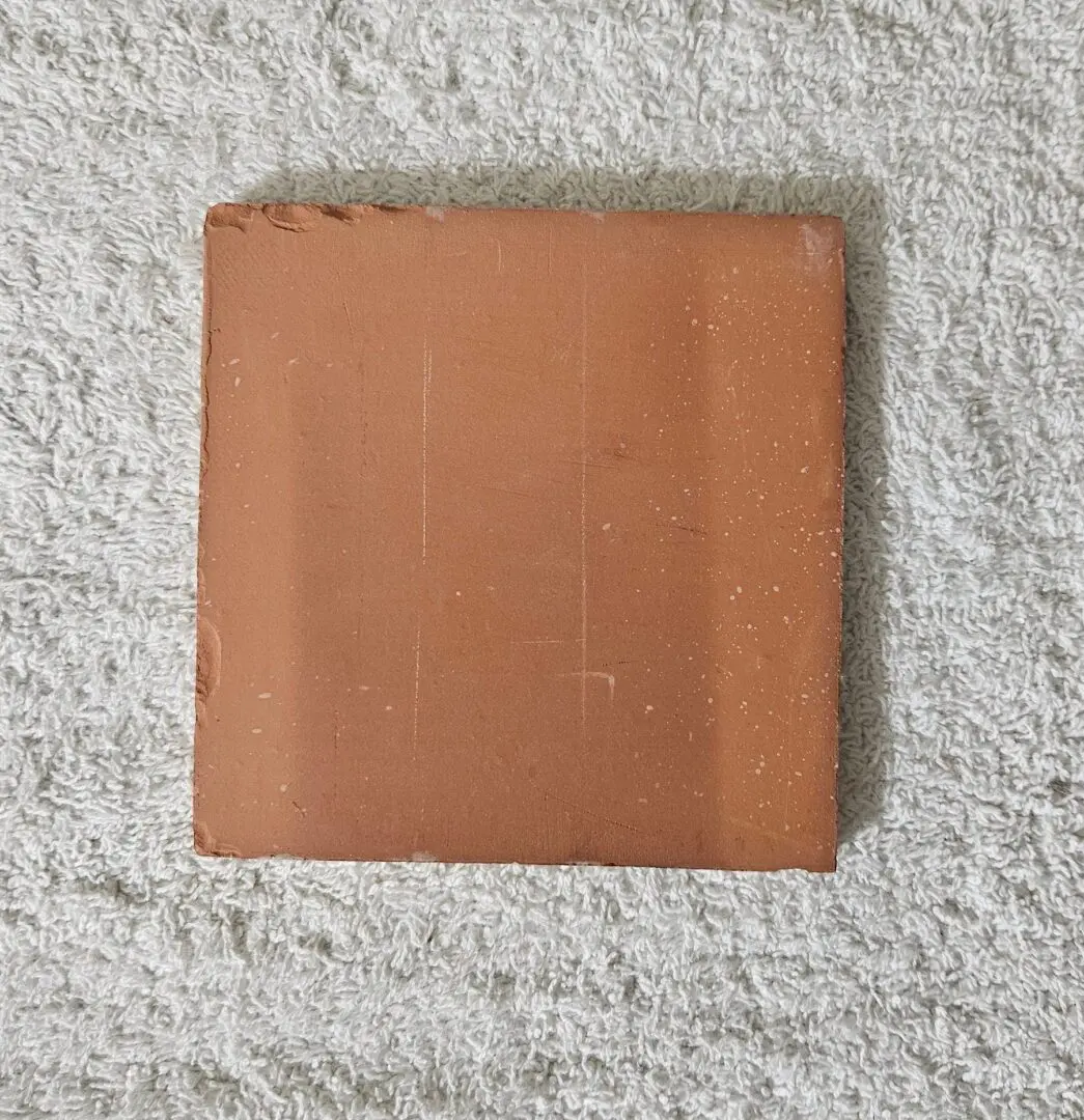 Square terracotta tile on textured towel