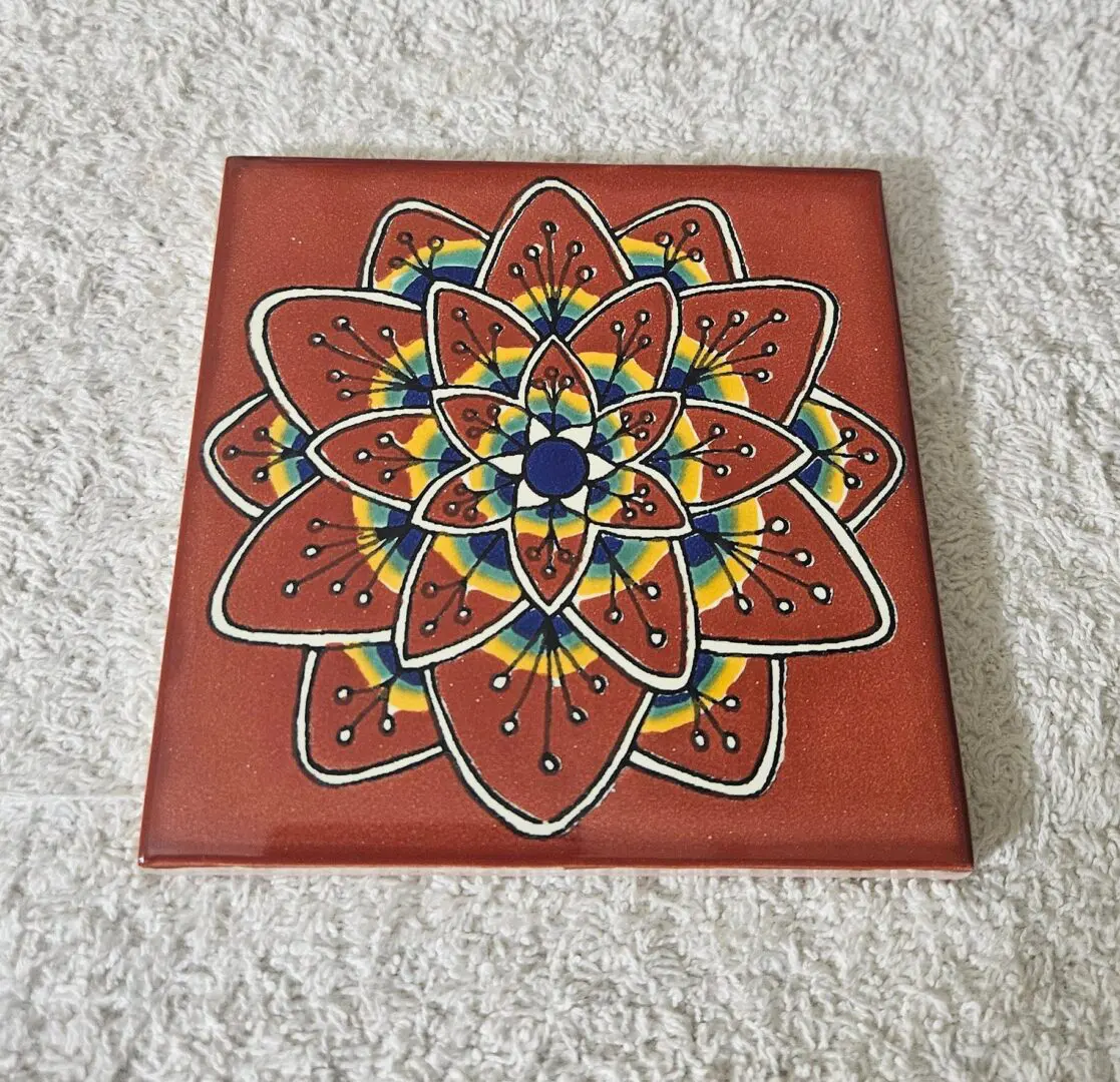Colorful mandala design on a square tile.