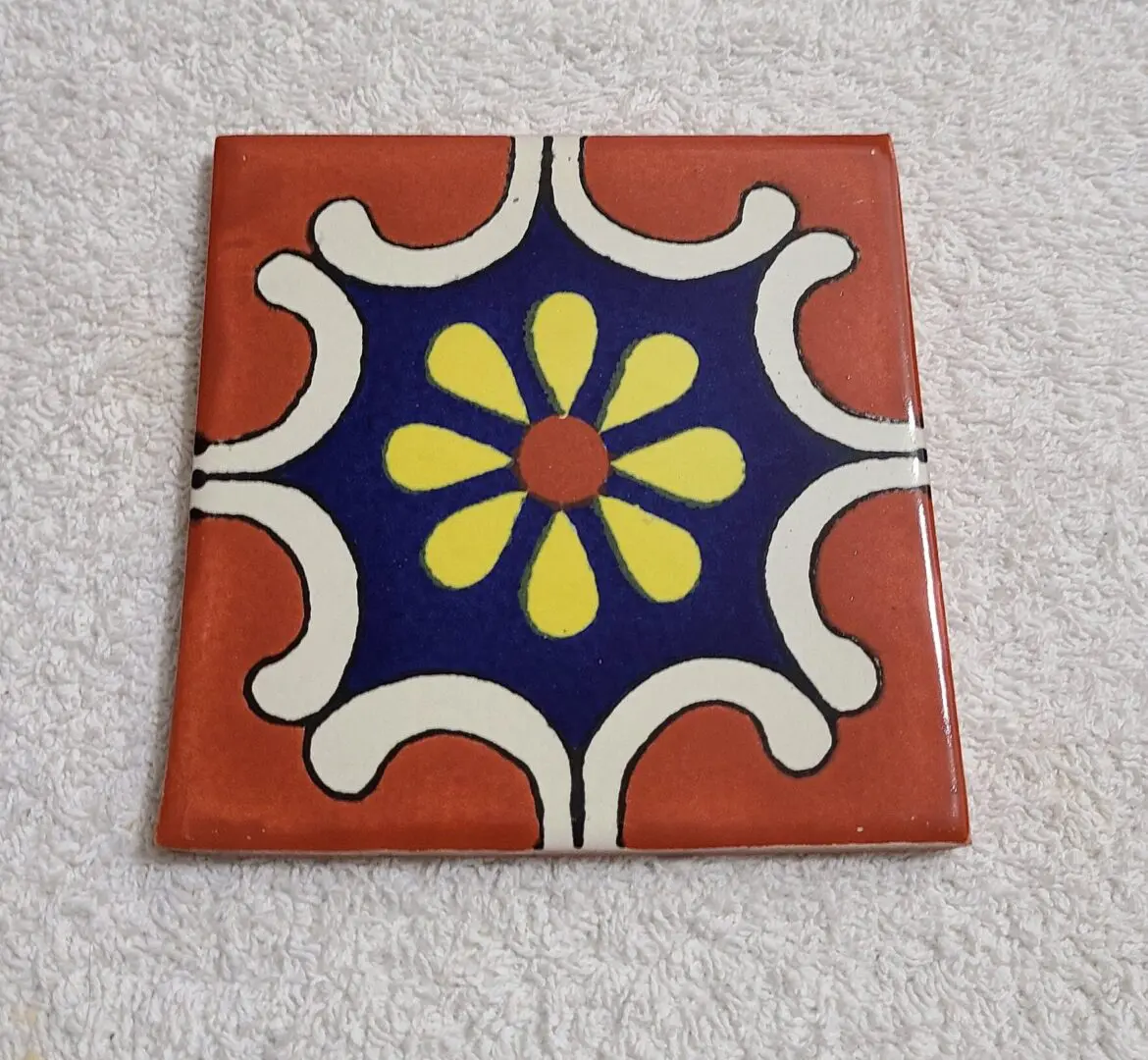 Decorative ceramic tile with colorful floral pattern.