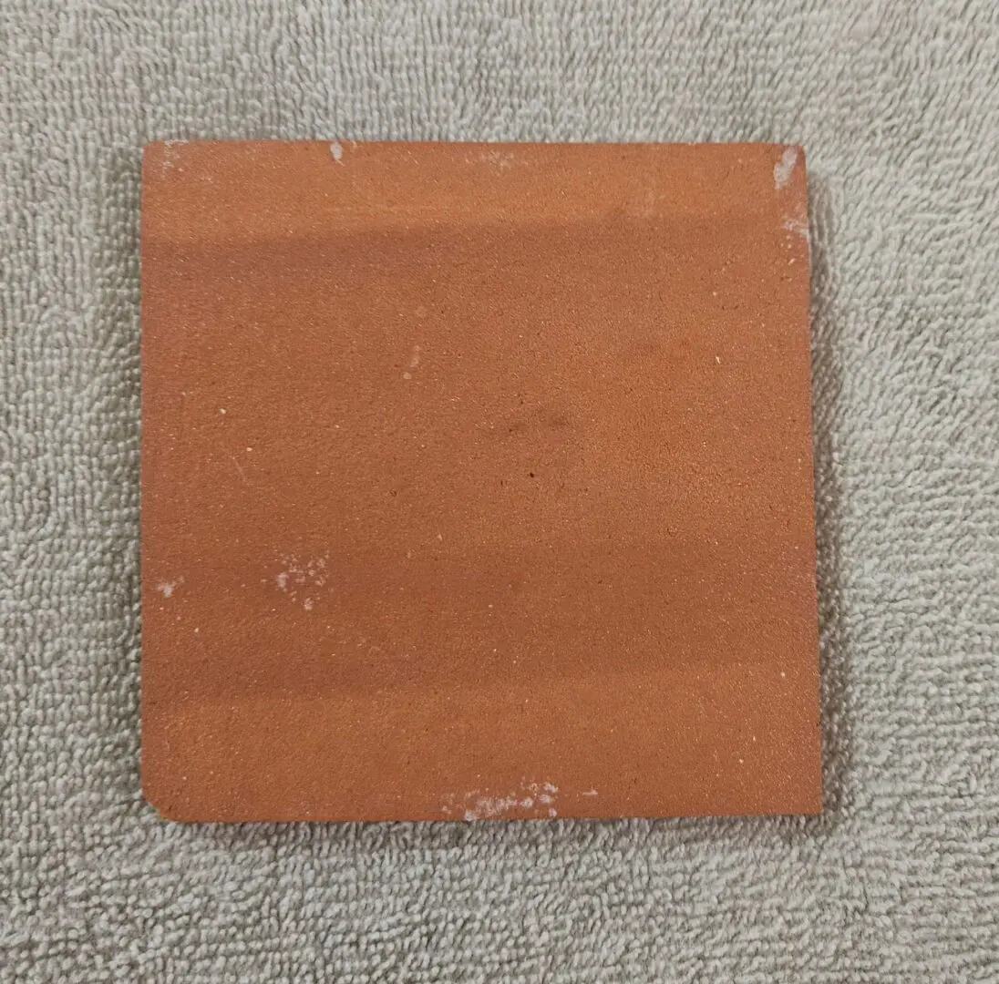 Square terracotta tile sample on towel
