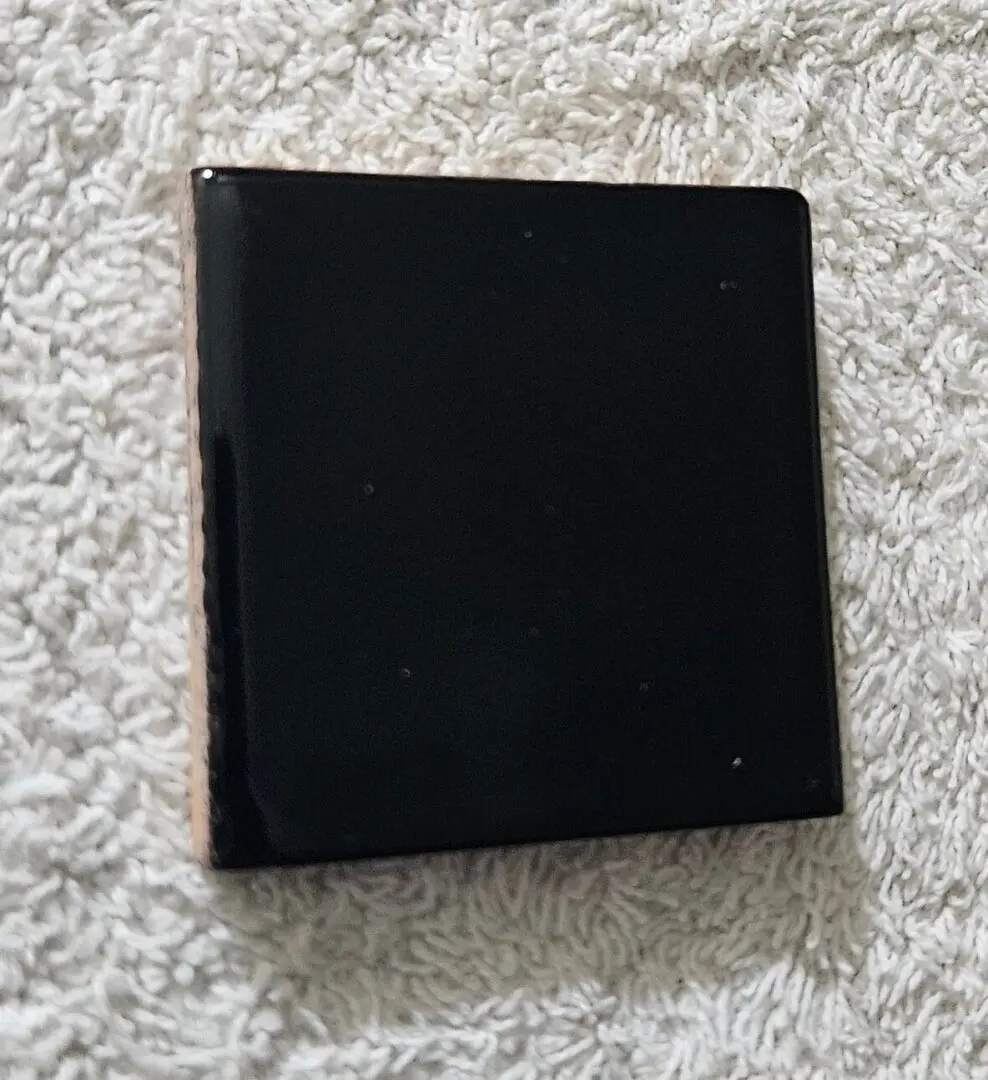 A black, square-shaped electronic device on a textured white surface.