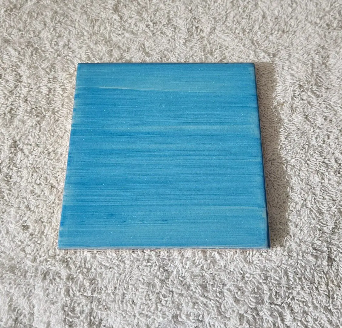 Blue ceramic tile on textured fabric.