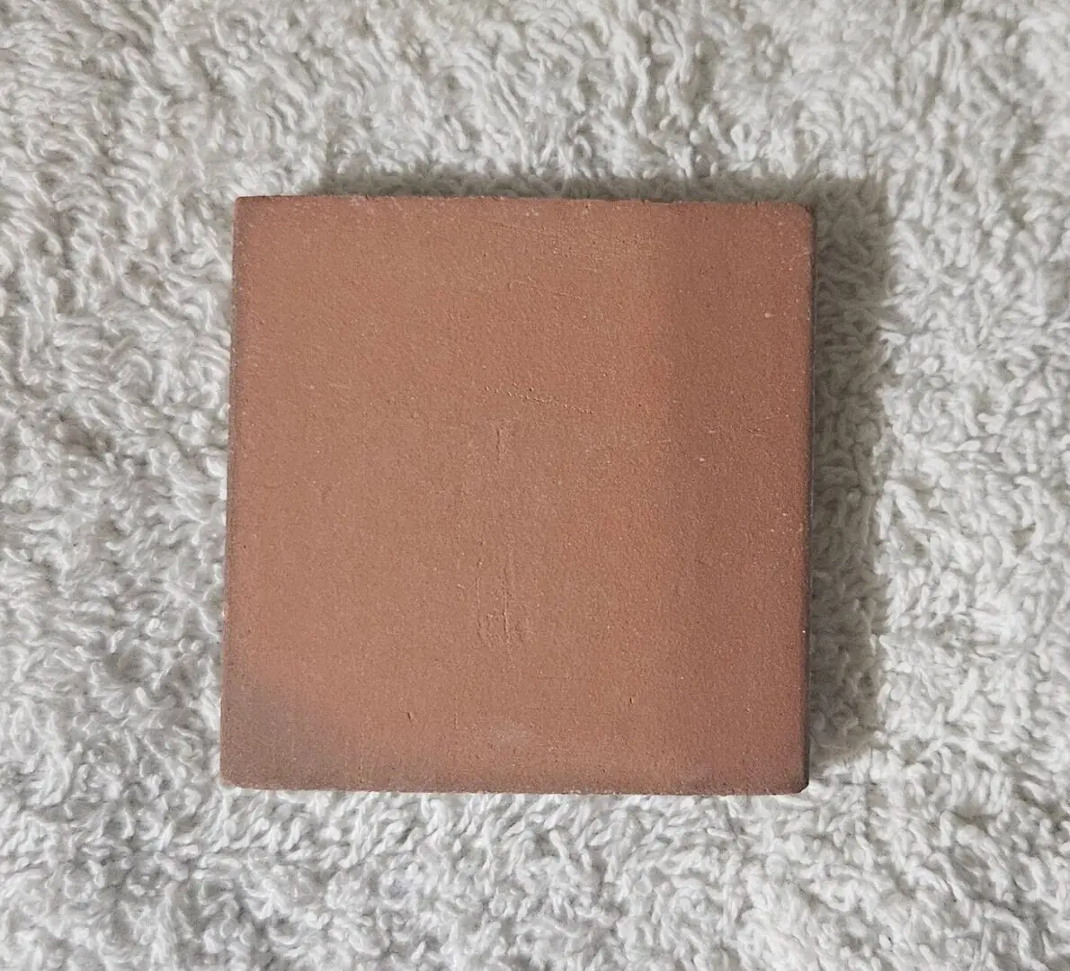 Square terracotta tile on textured white rug