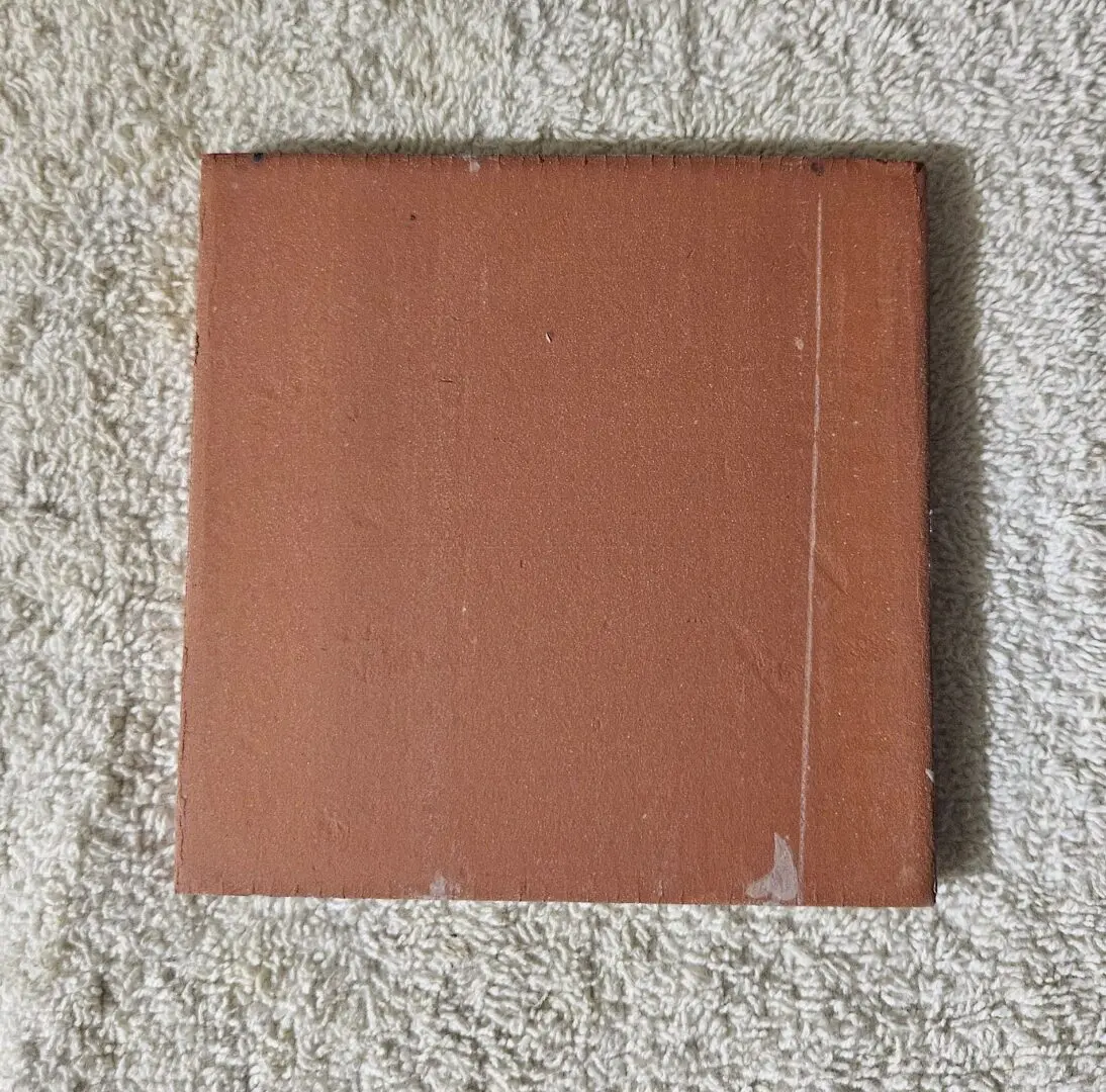 Square terracotta ceramic tile on textured towel