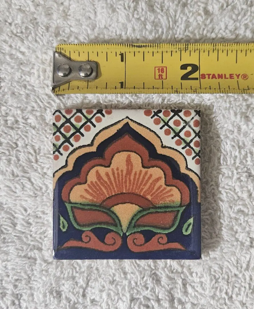 Decorative tile with measuring tape on towel.