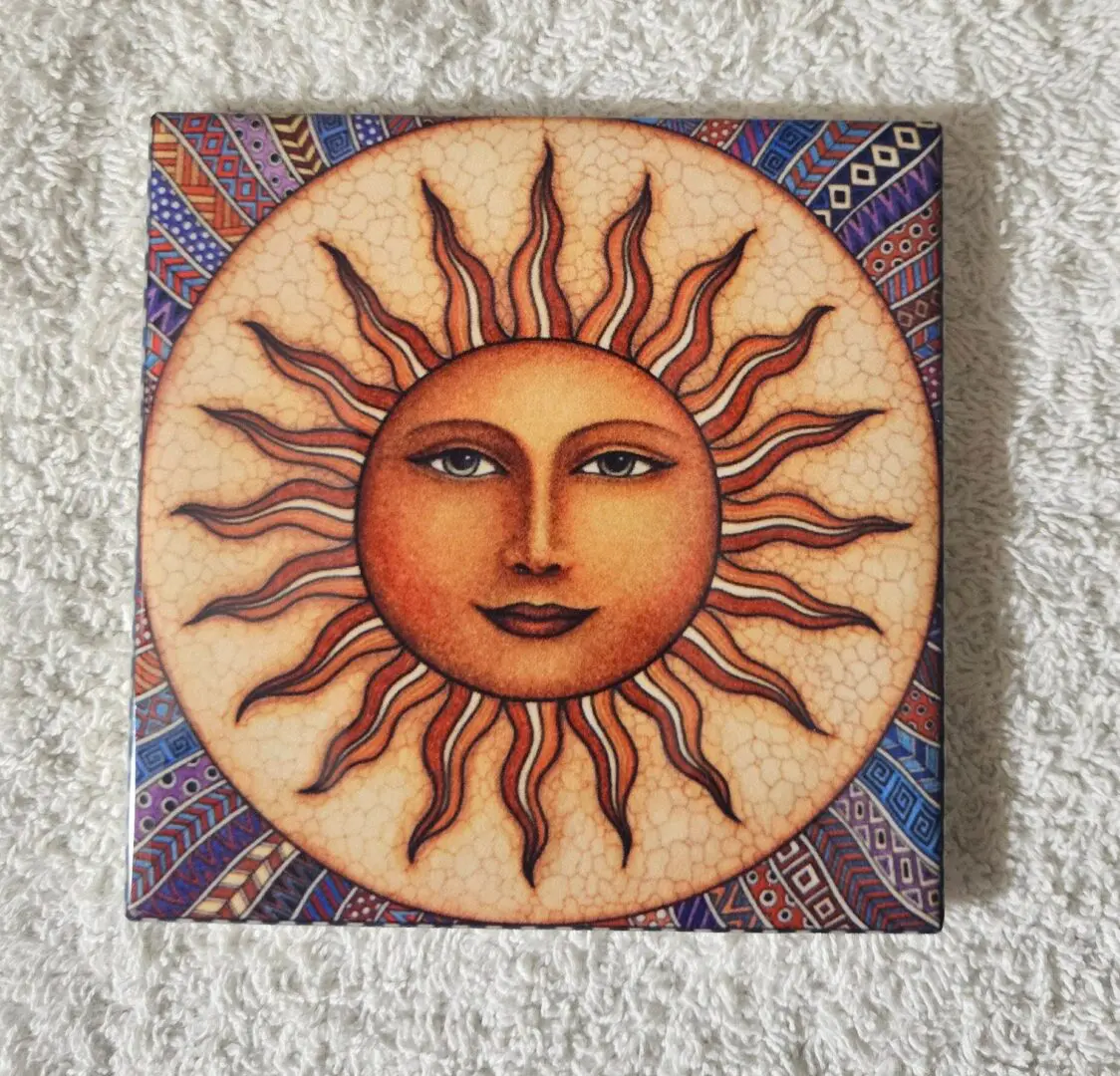 Sun face artwork on patterned tile.