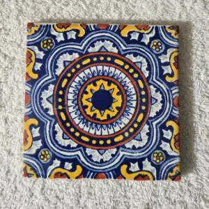Decorative ceramic tile with intricate blue, yellow, and white mandala pattern.