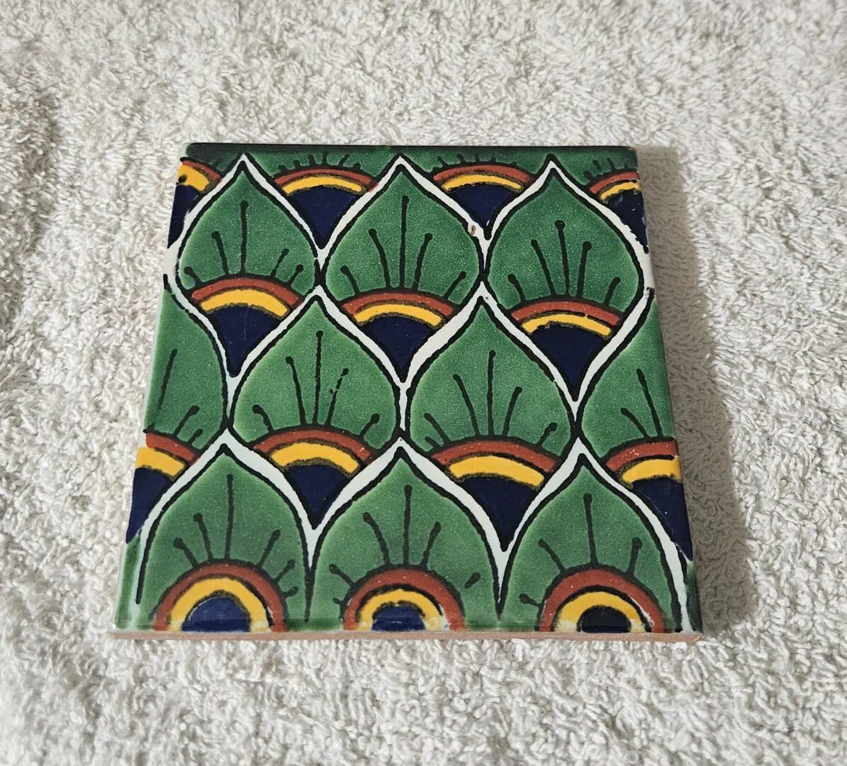 Fabric with green, yellow, and black fan-like patterns on a white surface.