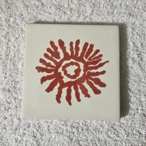 Tile with red sun-like pattern on white background.