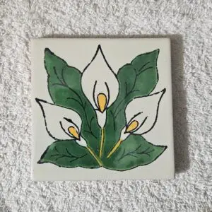 Hand-painted tile featuring white calla lilies with green leaves.