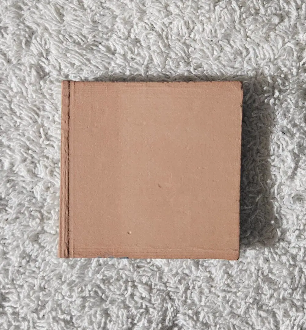 A closed brown hardcover book on a carpeted floor.
