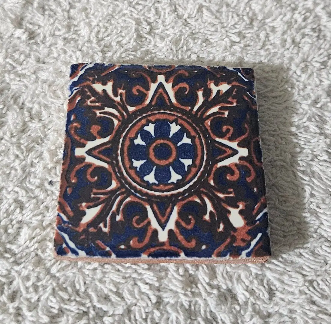 Ornate patterned tile on textured surface.