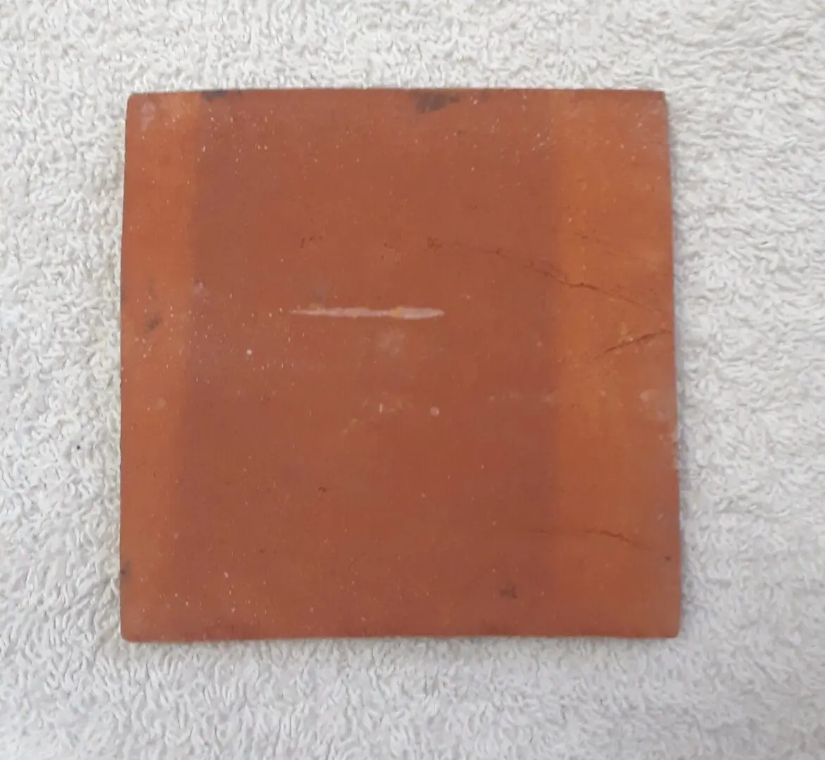 Square brown tile on a textured light background.