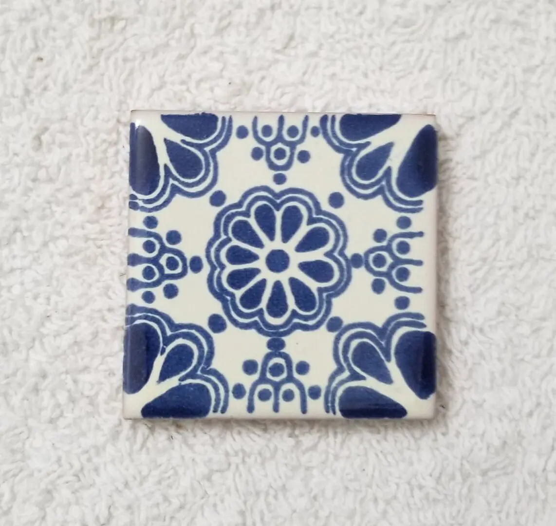 Square blue floral ceramic tile on towel