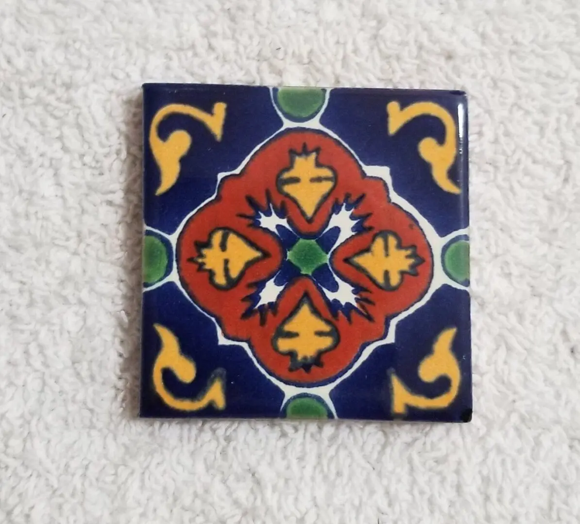 Decorative ceramic tile with a colorful symmetrical pattern.