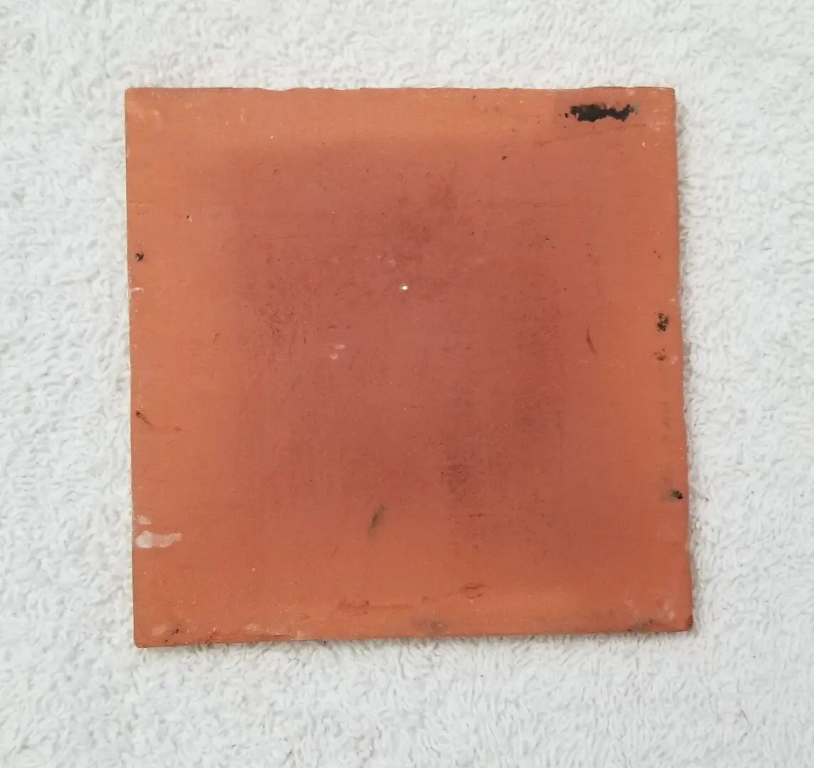 Scuffed square terracotta tile on white towel