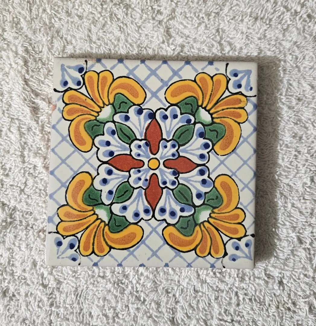Decorative ceramic tile with floral and heart patterns in yellow, green, and red.