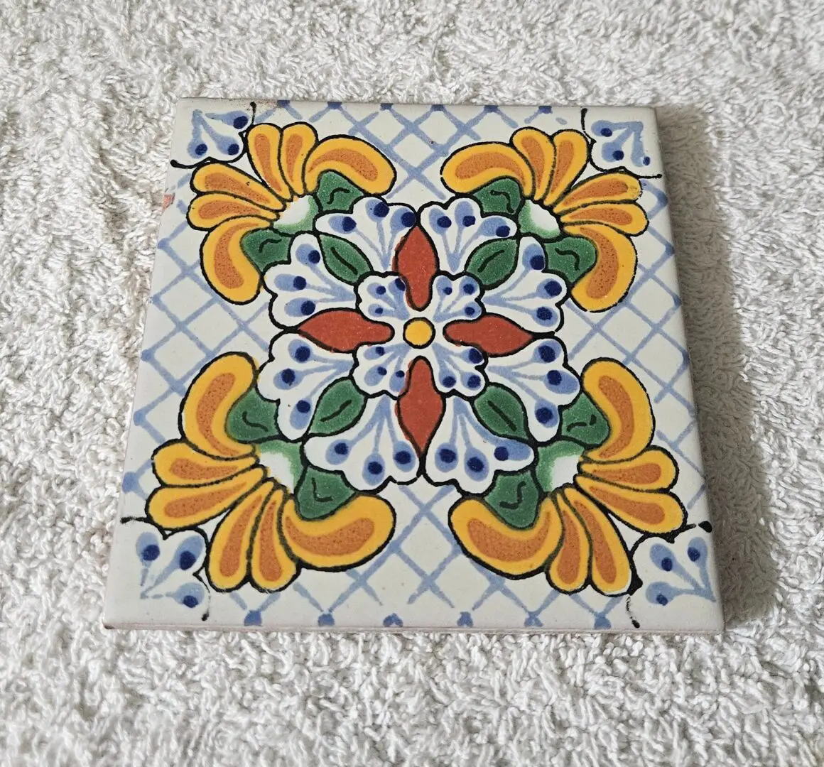 Decorative floral ceramic tile on white towel