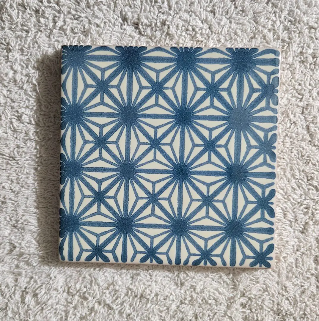 Blue geometric patterned tile on textured surface.