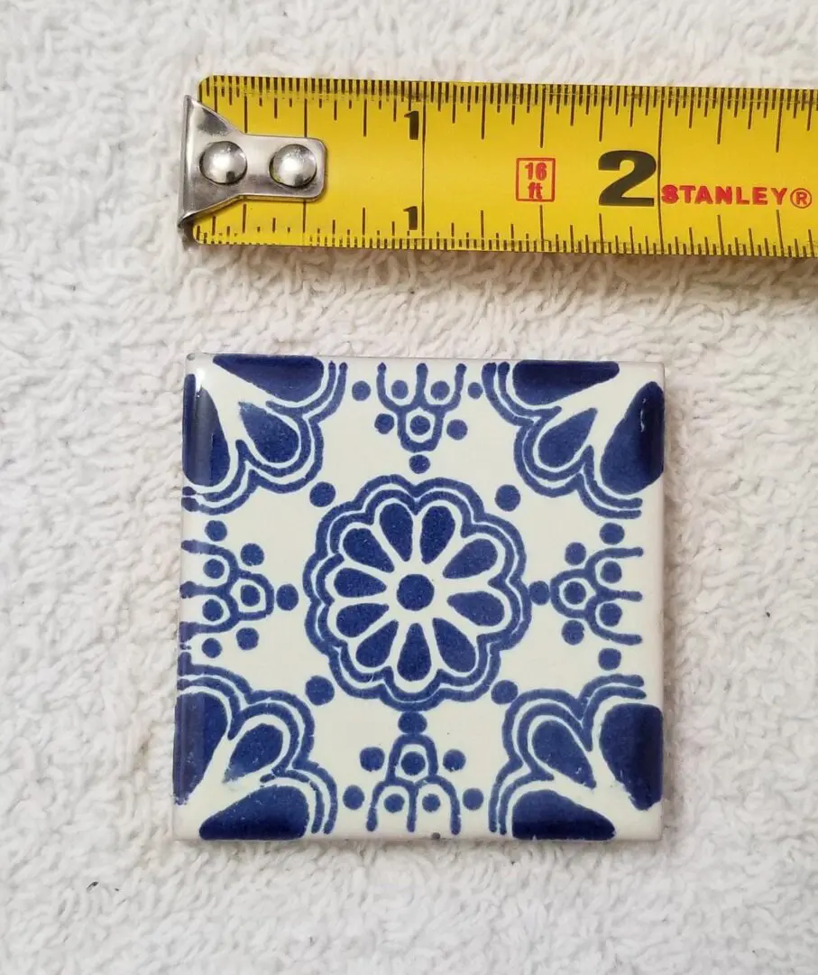 Tile with blue pattern, measuring tape above.