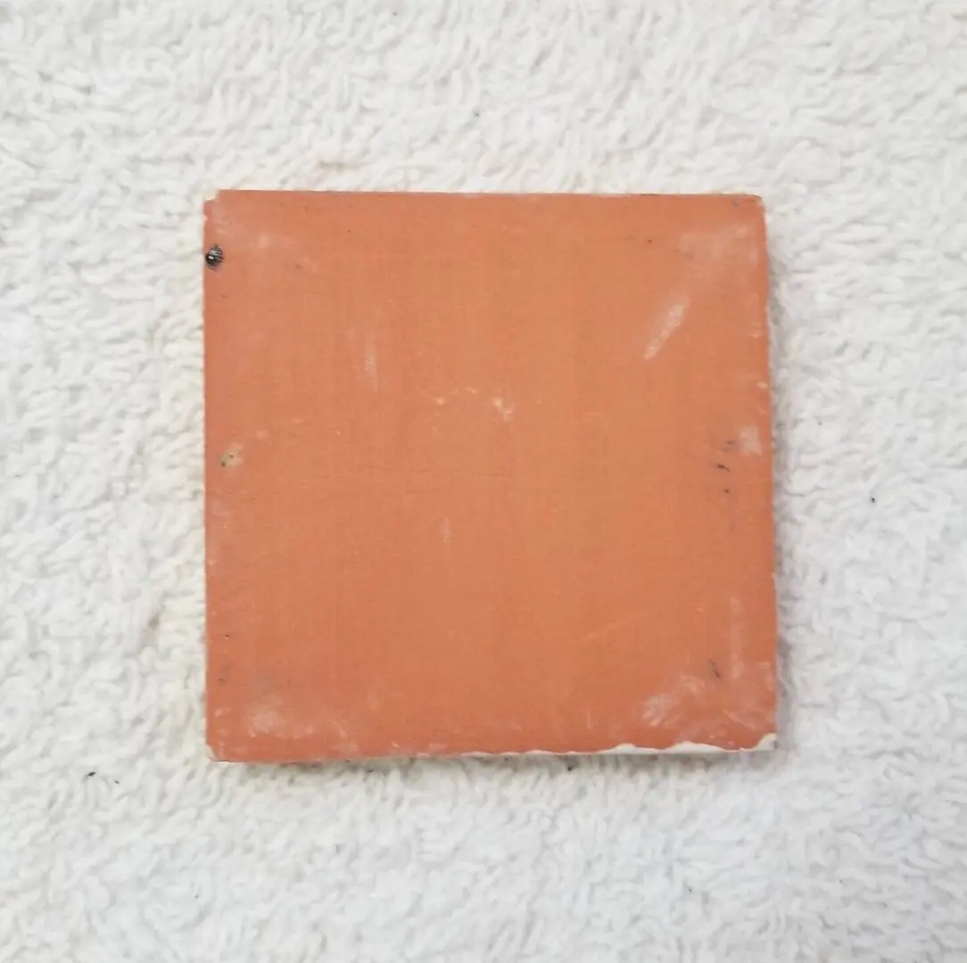 Square terracotta tile on white textured towel