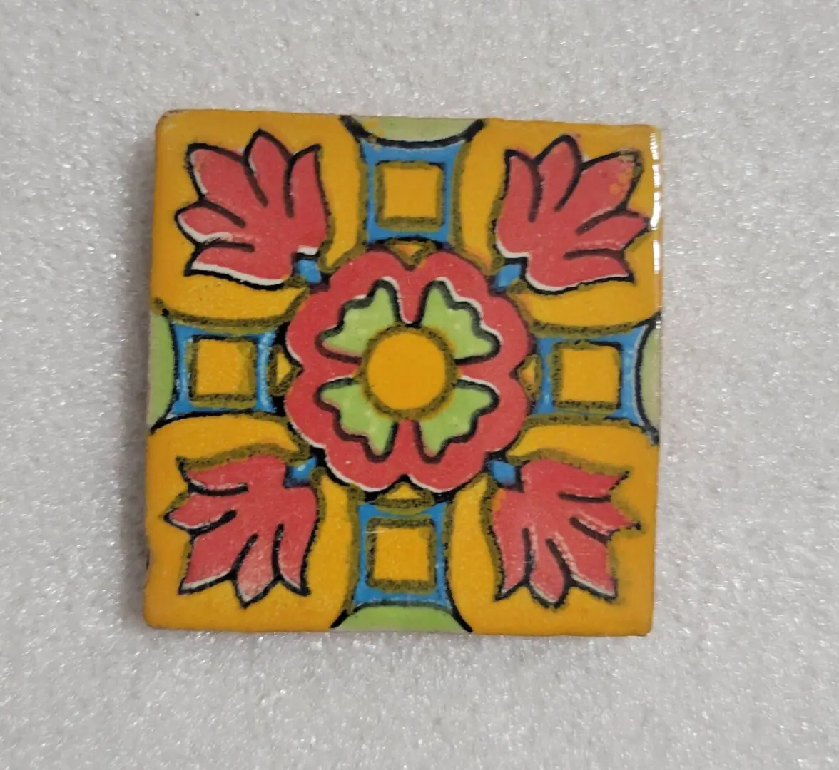 Colorful ceramic tile with floral pattern on yellow background.