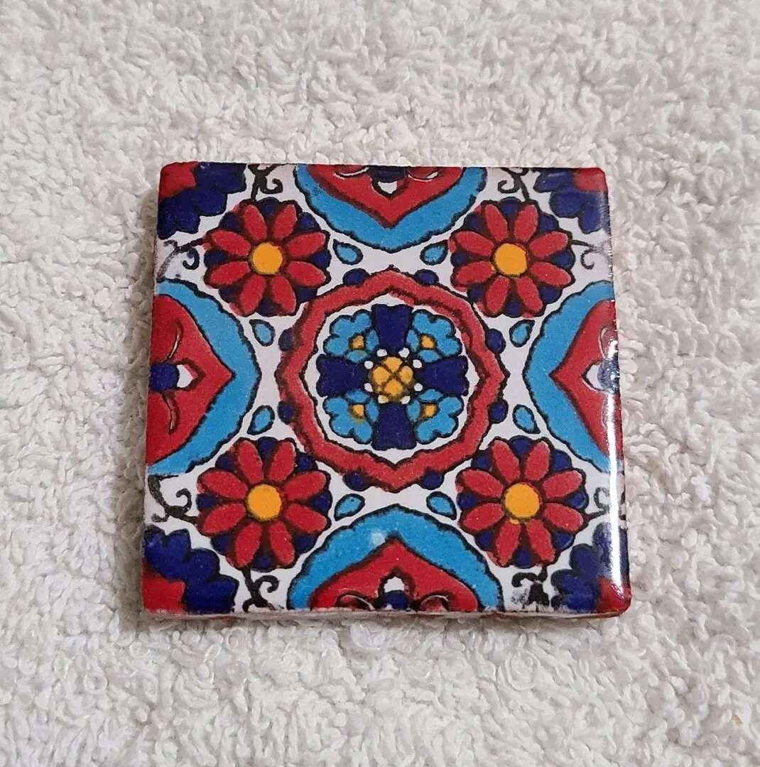 Colorful floral pattern tile on textured surface.