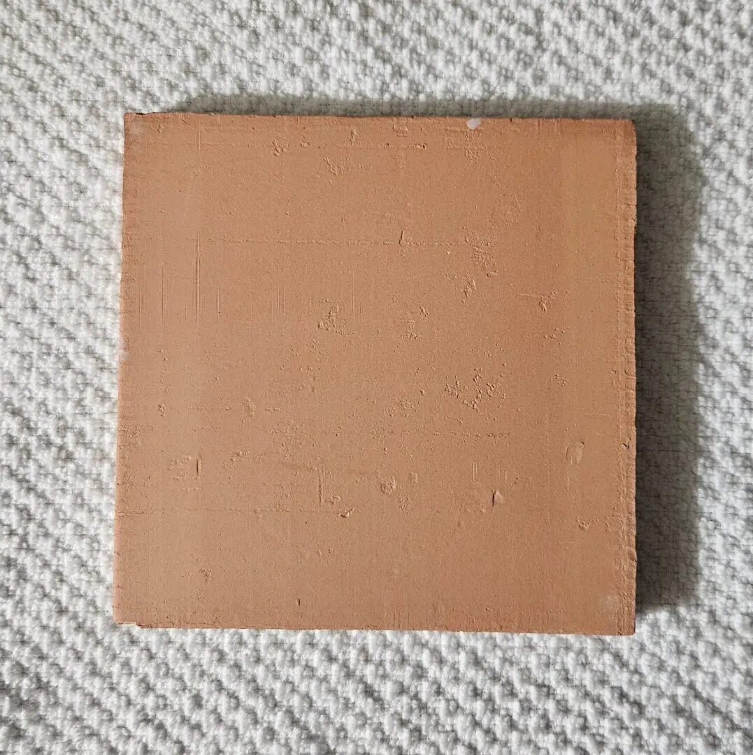 Square terracotta tile sample on textured fabric