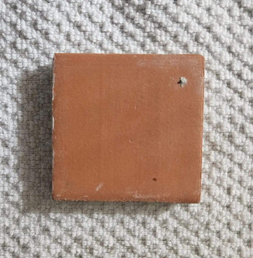 square terracotta tile sample on textured carpet