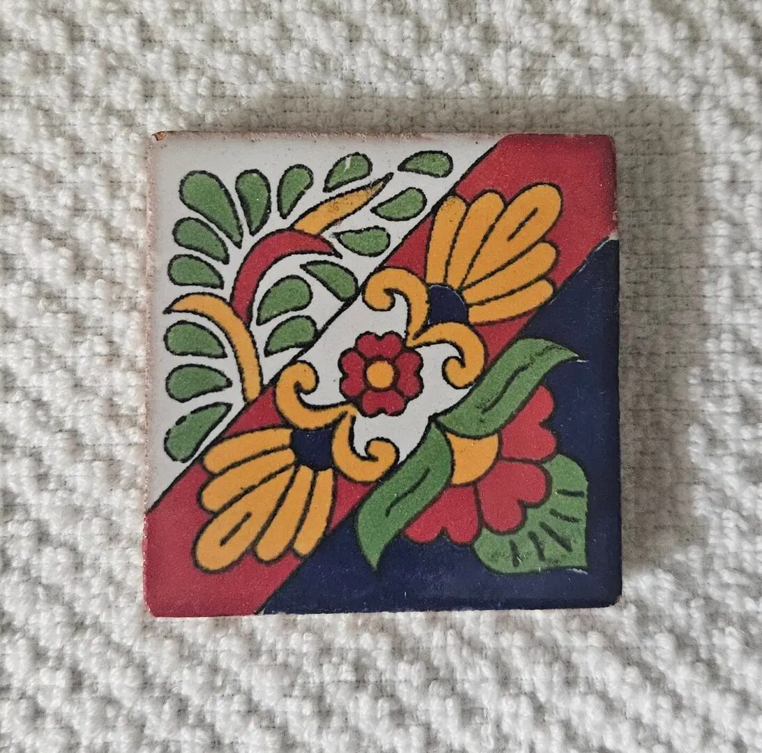 Colorful floral patterned ceramic tile on fabric.