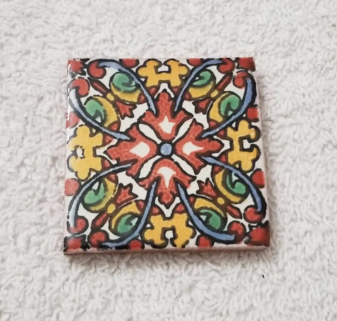Colorful decorative ceramic tile on textured background.