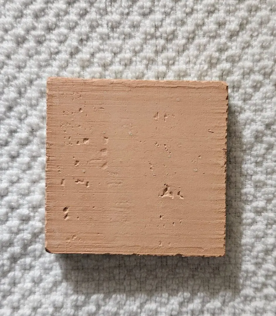 A square piece of light brown clay with surface imperfections.