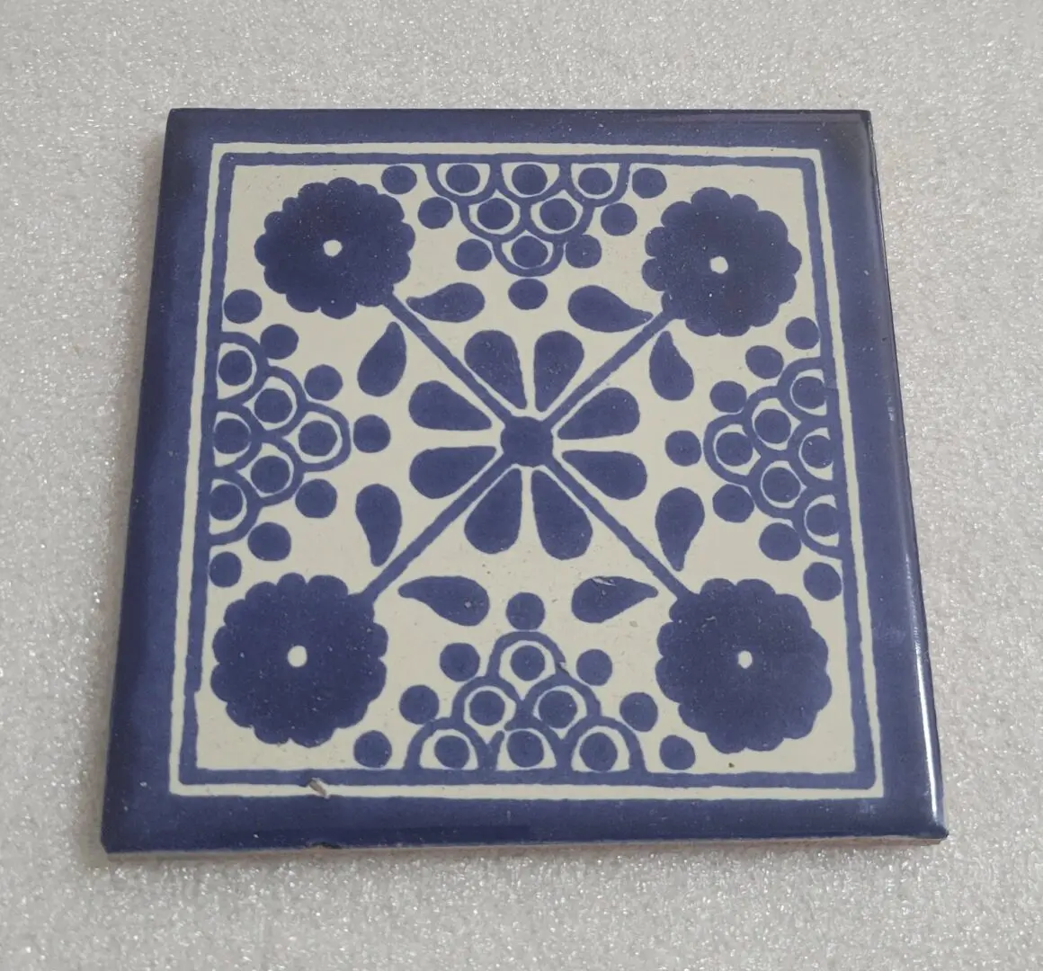 Blue floral patterned ceramic tile on surface.
