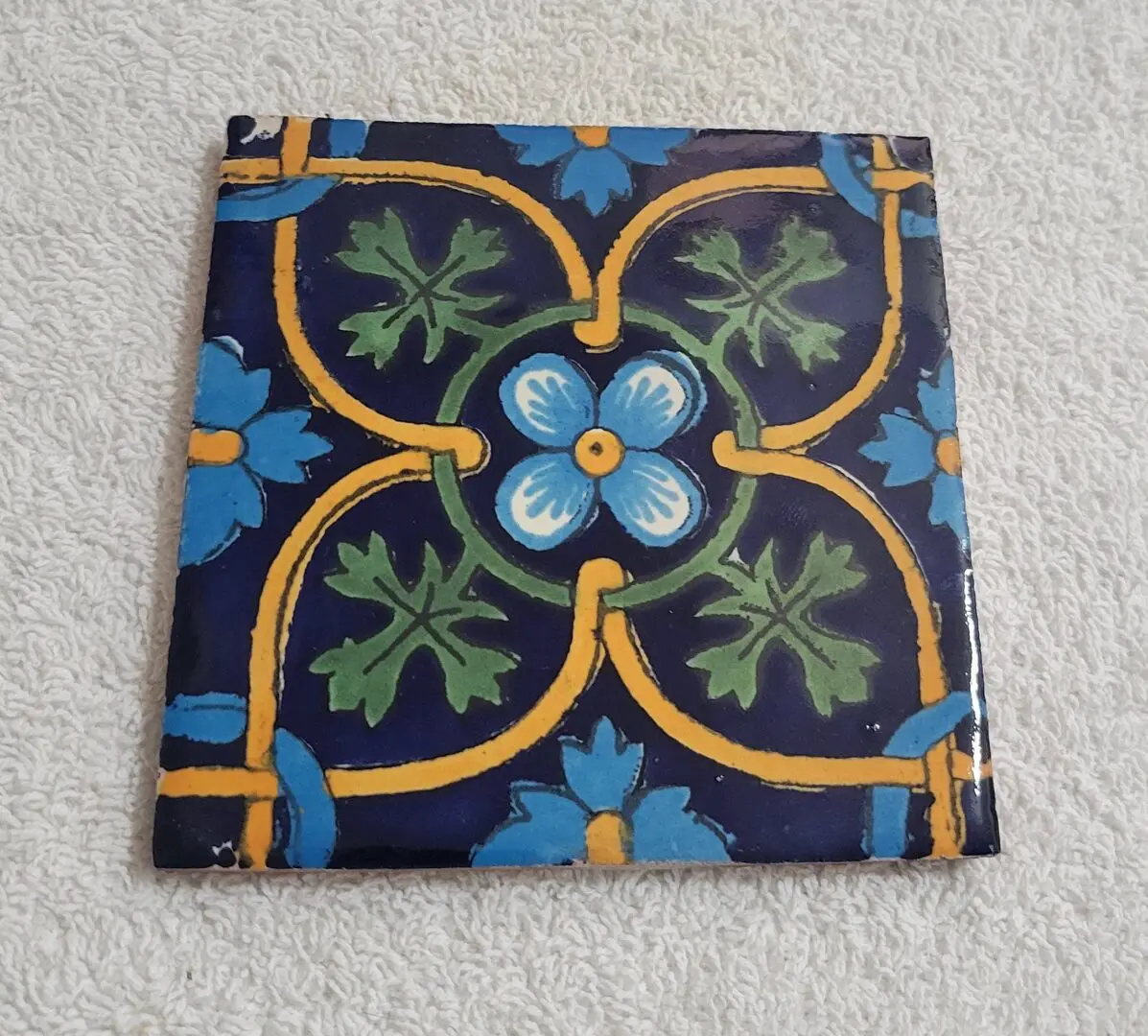 Colorful decorative ceramic tile with floral patterns on a blue background.