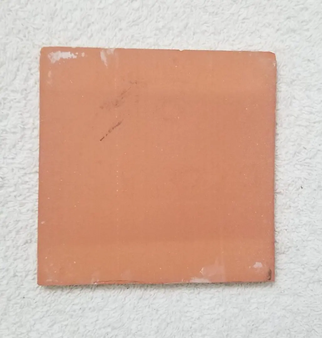 Square peach-colored tile with minor scratches on a white surface.