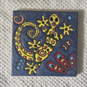 Colorful decorative tile featuring a stylized lizard and abstract designs.