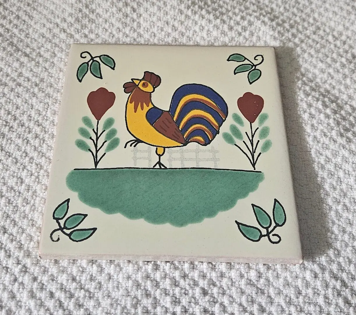 Decorative tile featuring a colorful rooster and floral designs.