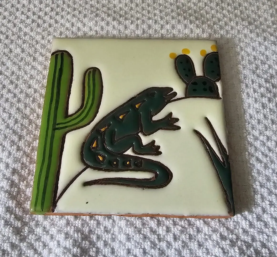 Lizard and cacti on decorative ceramic tile.