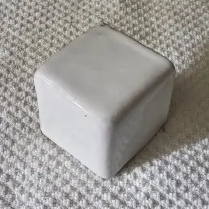 White cube on textured carpet surface.