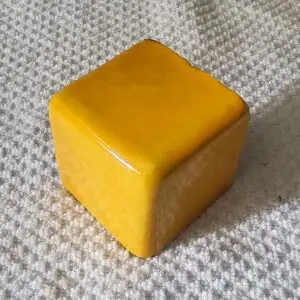 A small yellow cube resting on a textured surface.