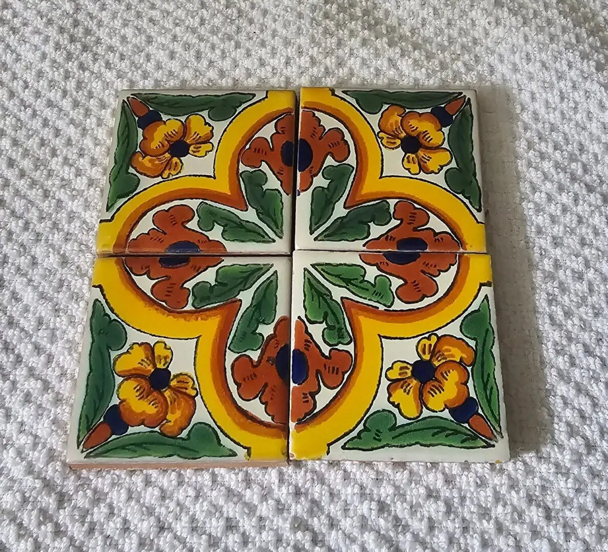 Colorful floral ceramic tiles on textured surface.