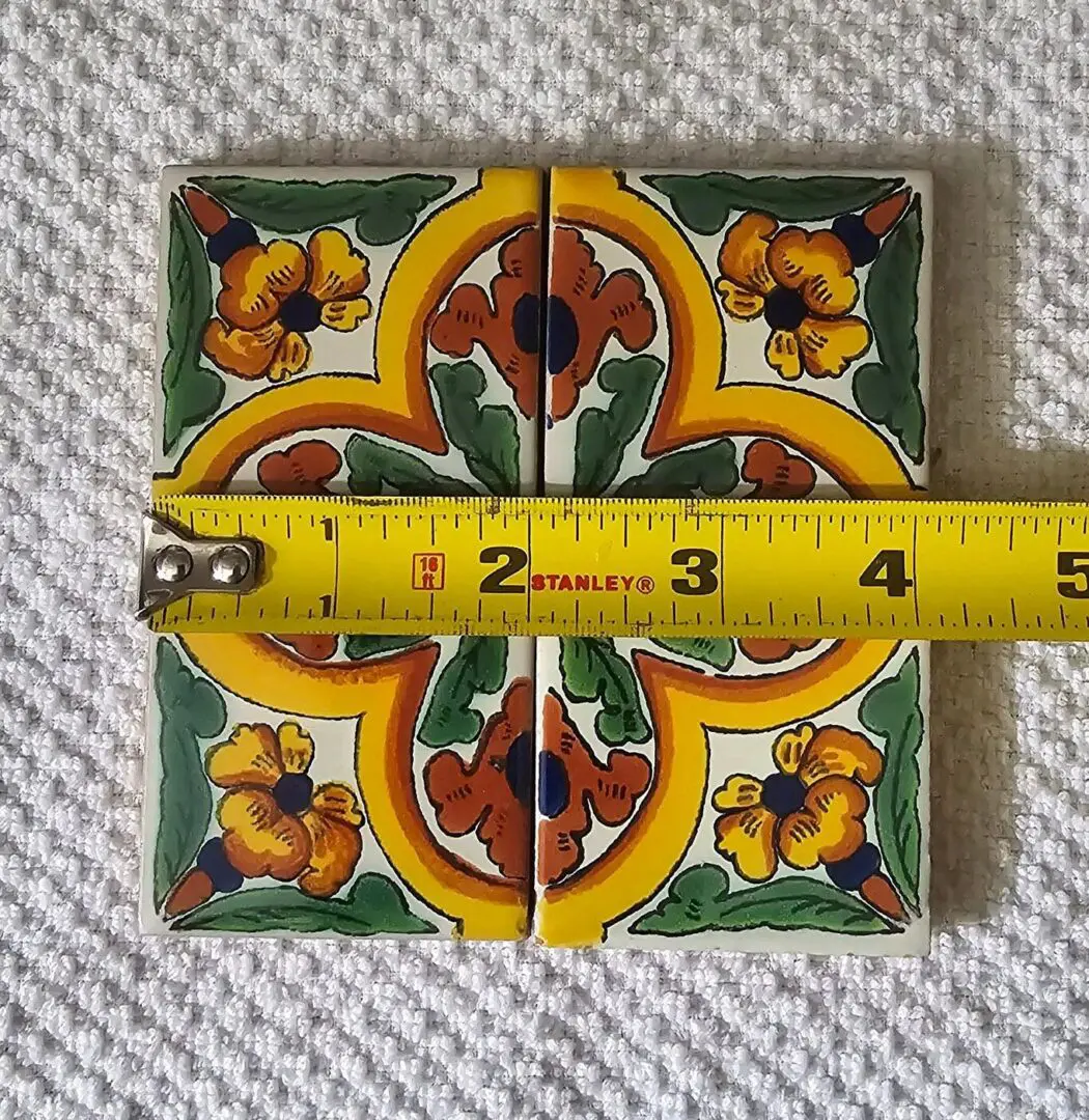 Colorful tiles measured with yellow tape measure.