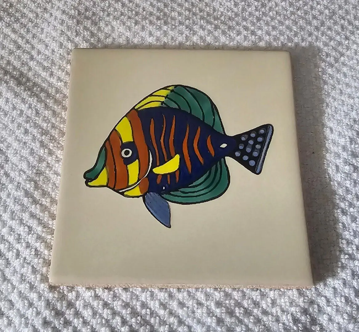 Colorful fish artwork on ceramic tile.