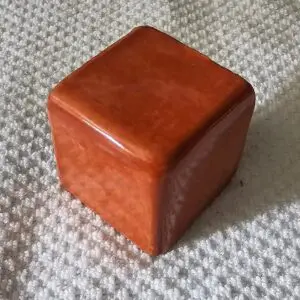 Brown cube on textured surface.