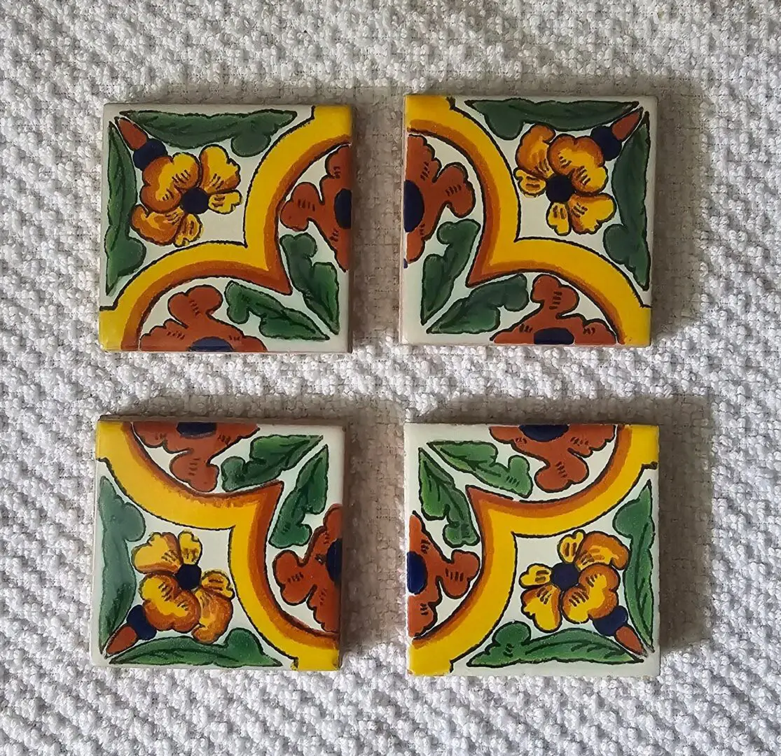 Four colorful decorative tiles on textured surface.