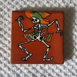 Dancing skeleton with colorful hat on tile.